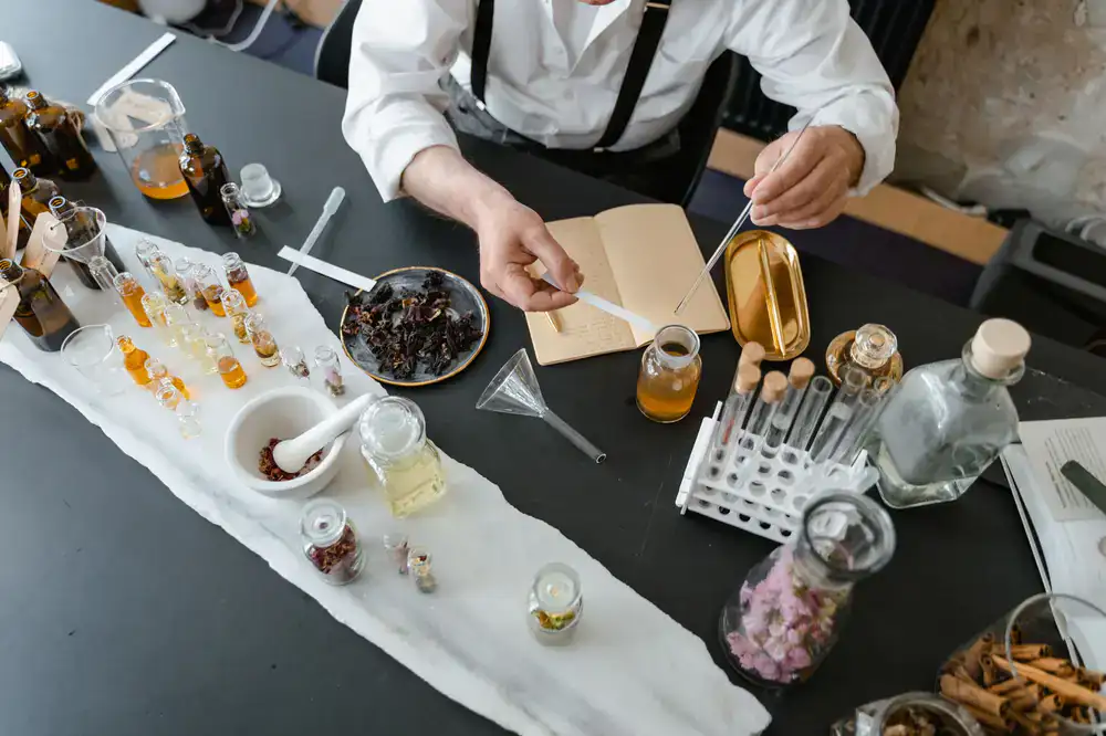 Artisan perfume bottles, pipettes, and raw botanical materials on a work desk