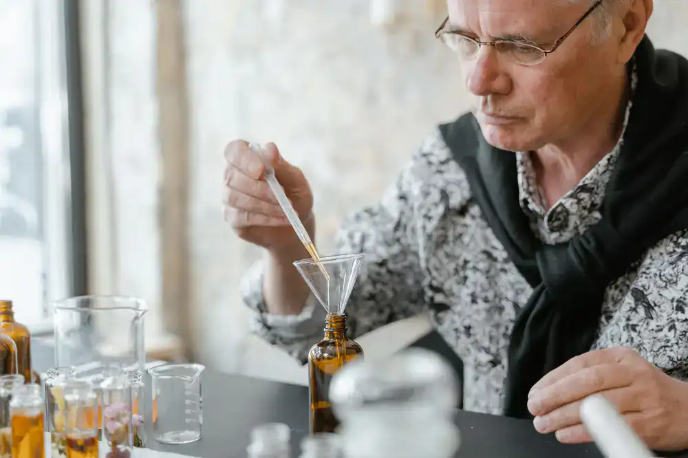 Close up of an artisan perfumer filtering a golden fragrance blend