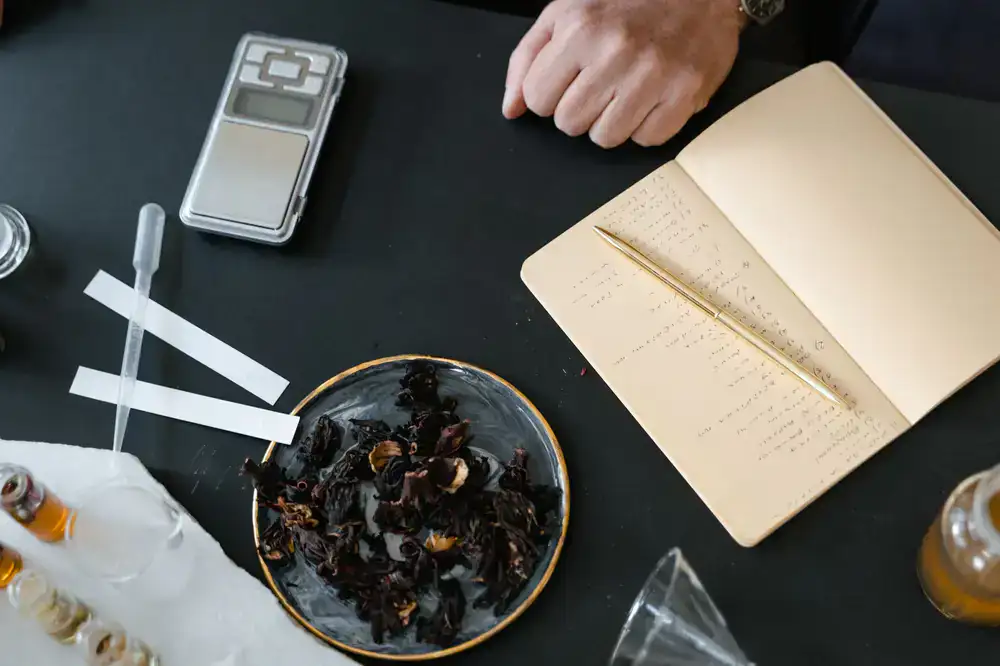 Raw botanical ingredients and a brass scale on a perfumer workbench