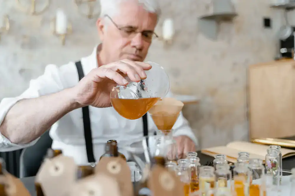 Artisan instructing a guest on fragrance blending at a wooden workbench